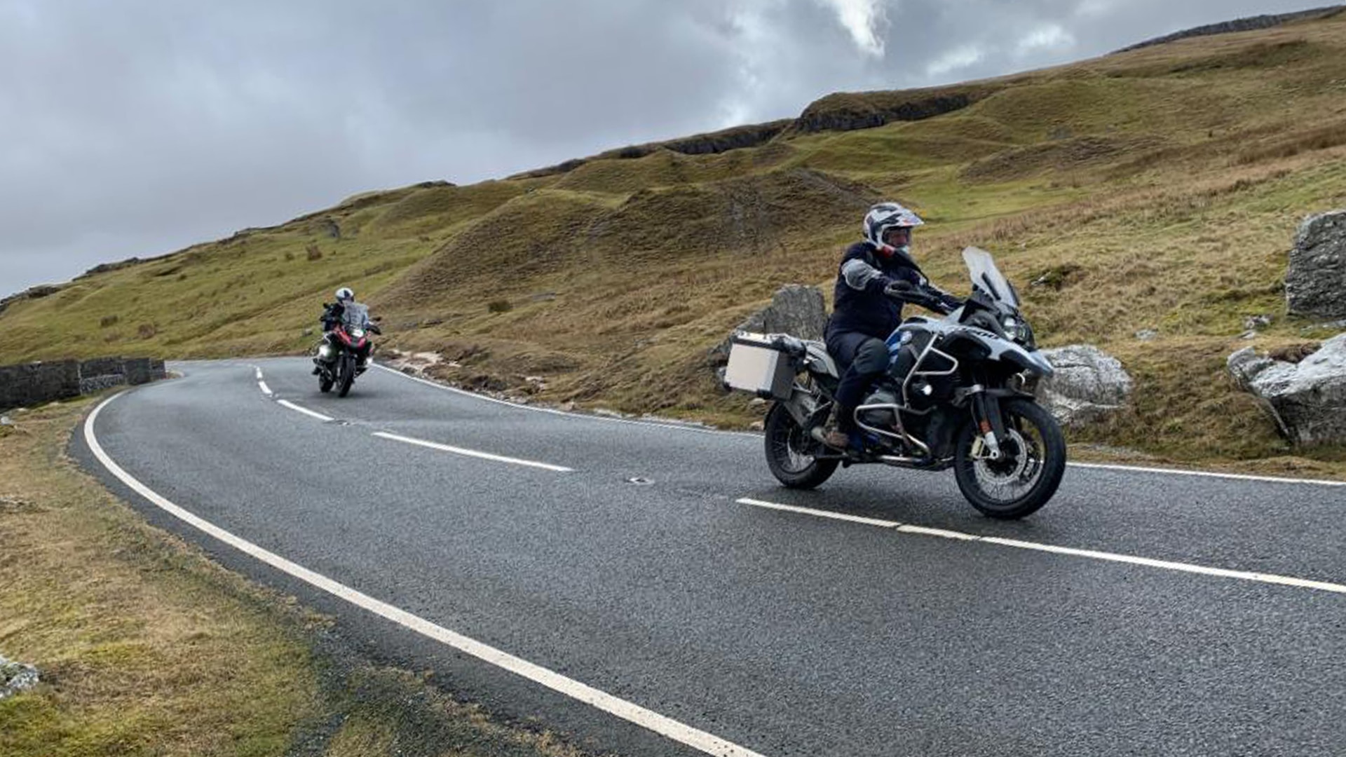 We see two motorcyclists on a country road.