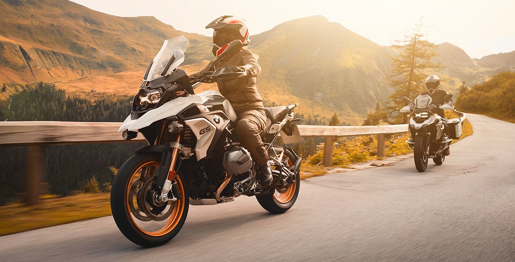 Close-up of a standing R 1250 GS in sunlight with the motorcyclist in the background